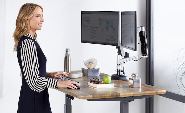 woman smiling while working on a standing desk