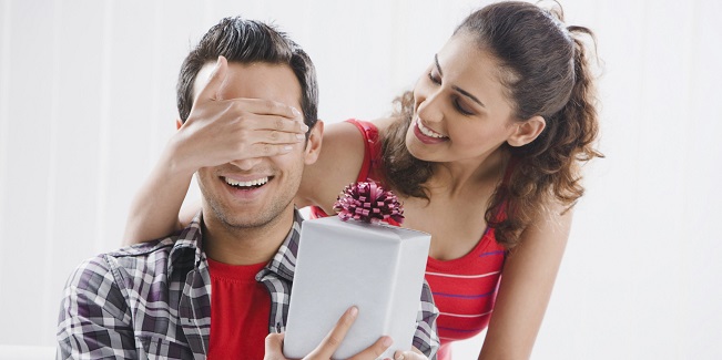 woman suprising man with a present