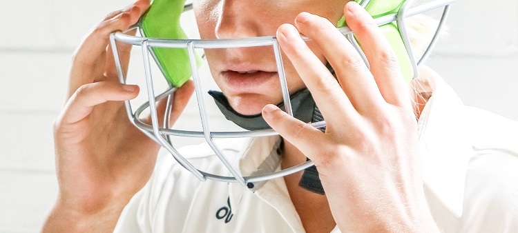 man putting on a cricket helmet 