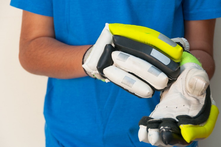 man putting on cricket gloves