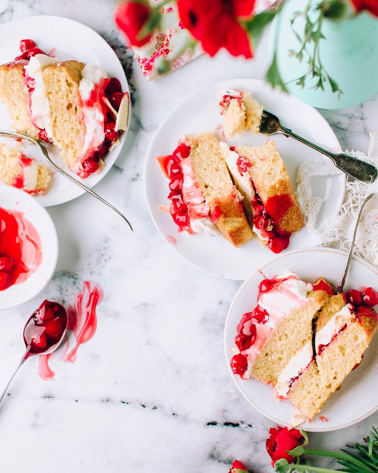 tasty vanilla and cherry cake slices on plates on table 