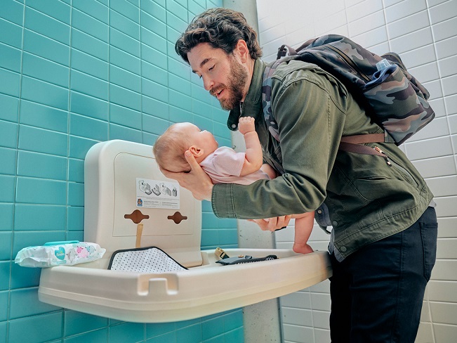 dad changing his baby with diaper accessories while travelling