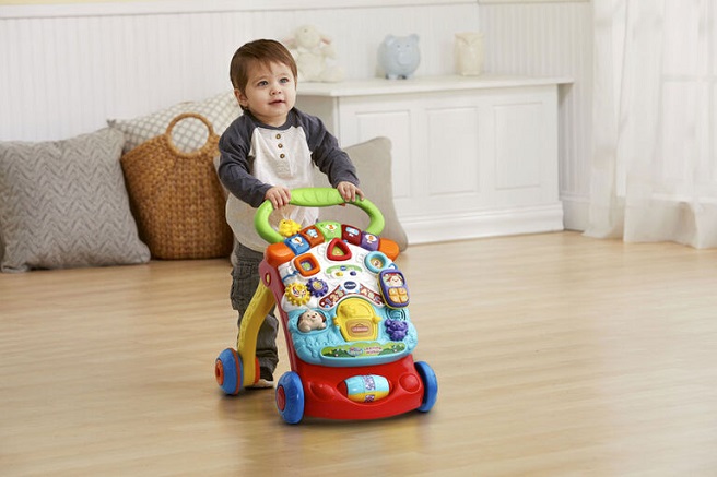 picture of a baby with an activity center walker on a floor in the living room 