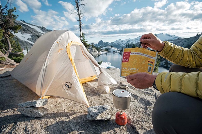 Close up of having a freeze dried meal near a tent with a great view
