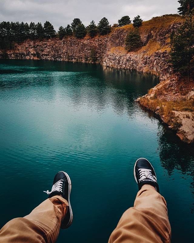 picture of a person sitting beside a lake in a mountain