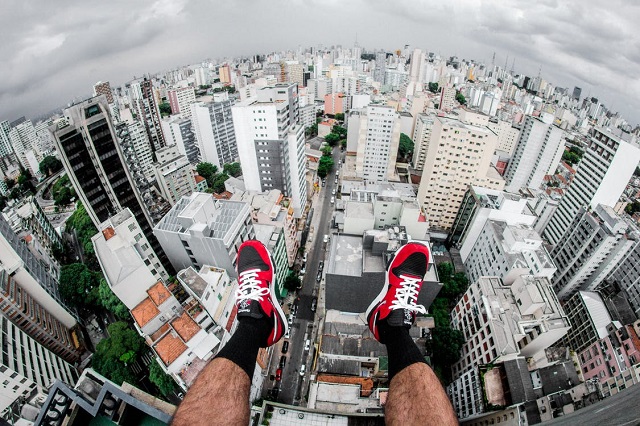 person sitting on top of a building with his outdoor footwear in the air 