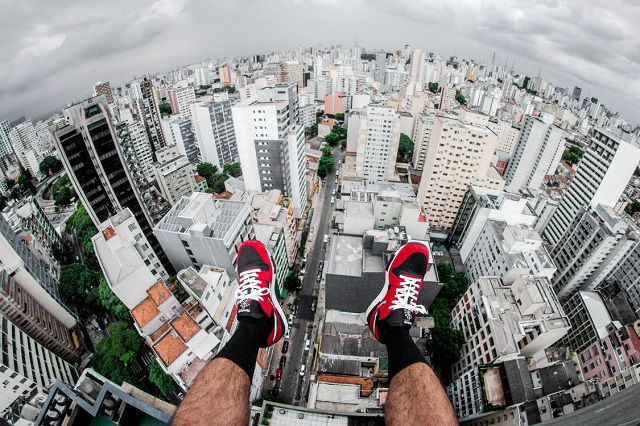 person sitting on top of a building with his outdoor footwear in the air