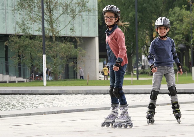 picture of two kids driving rollerblades in a park 