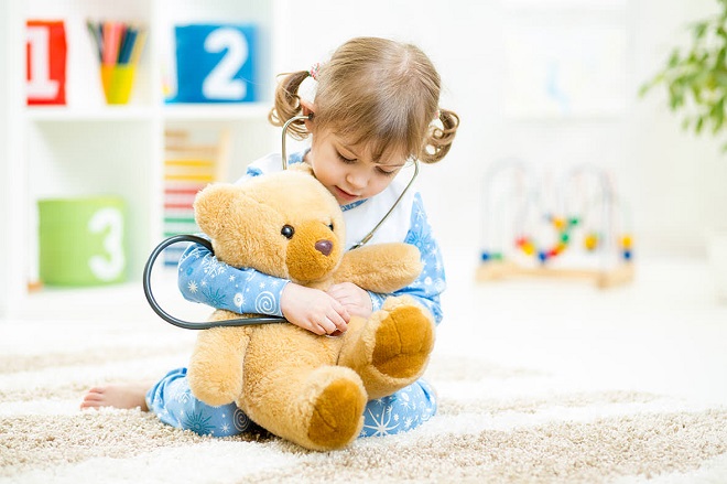 picture of Cute kid girl playing doctor with plush toy at home