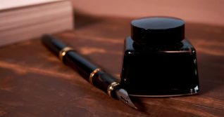Ink bottle and fountain pen on the wooden table