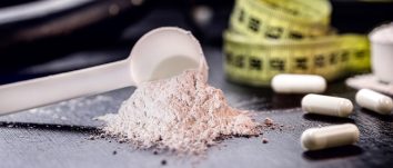 a scoop of pre-workout powder, measuring ape and capsules on a table