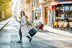 Fashionable young woman crossing the street with a black tote bag in a city setting.