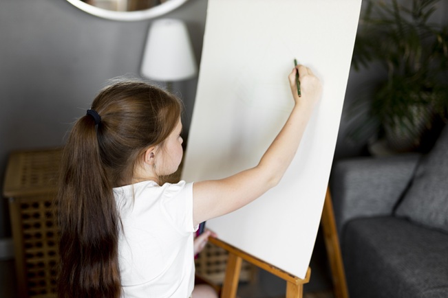 little girl painting on an easel
